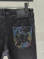 Dark denim jeans close-up of waist tag and blue graphic patch on the front pocket.