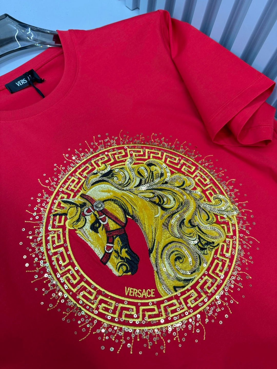 Versace red T-shirt close-up of gold lion medallion with VERSACE logo, short sleeves