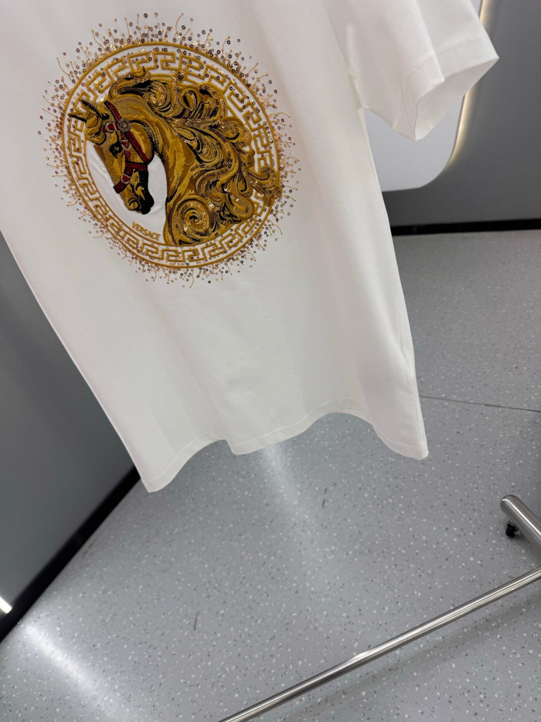 Front view of white T-shirt with gold horse emblem print and dotted detailing