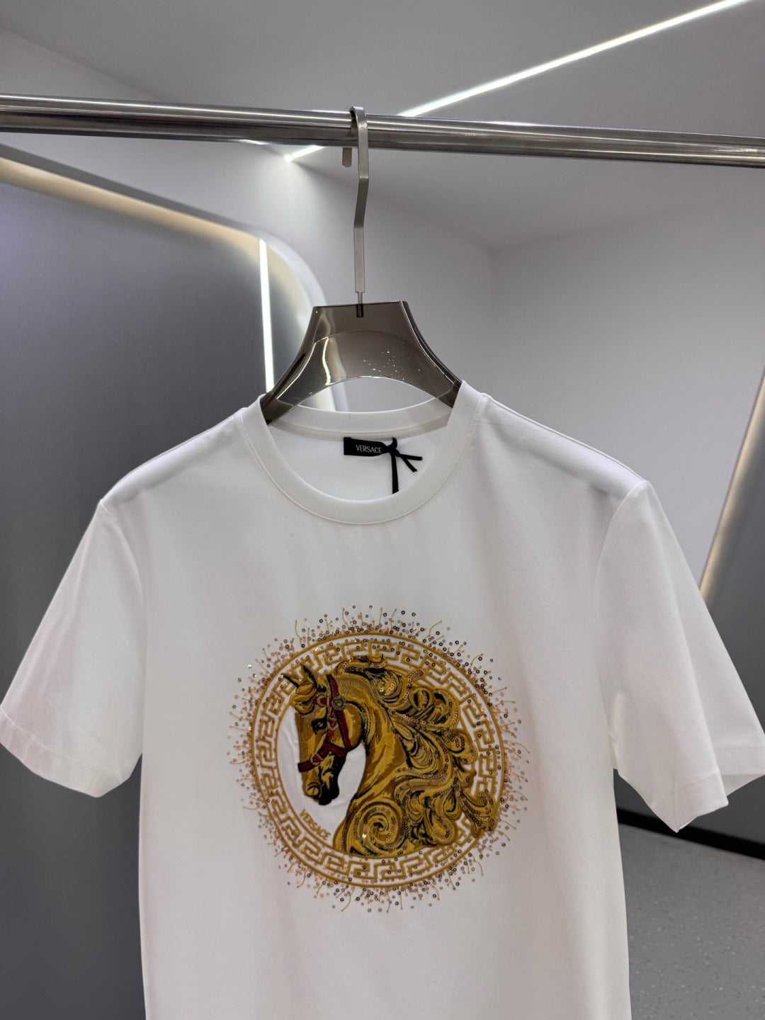 White crew-neck T-shirt with centered gold horse crest emblem on the chest