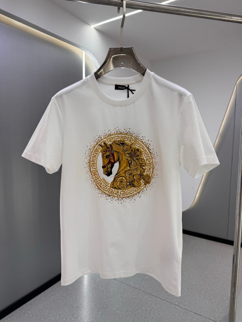 White crew-neck T-shirt with gold and black horse emblem print at the chest