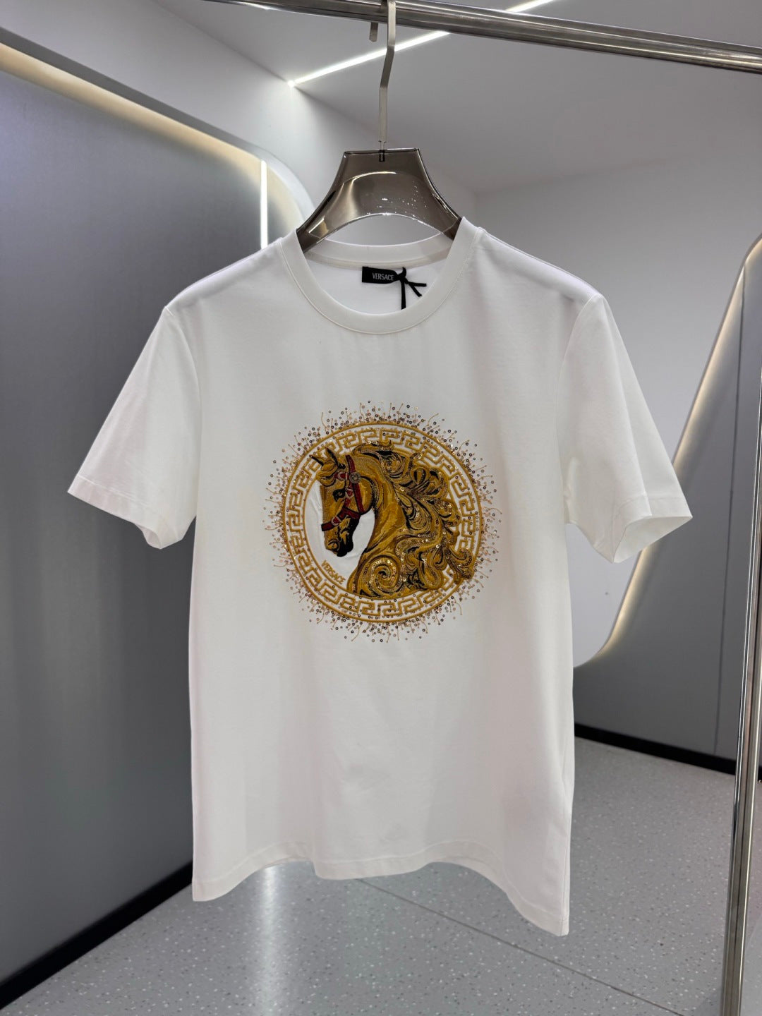 White crew-neck T-shirt with gold and black horse emblem print at the chest
