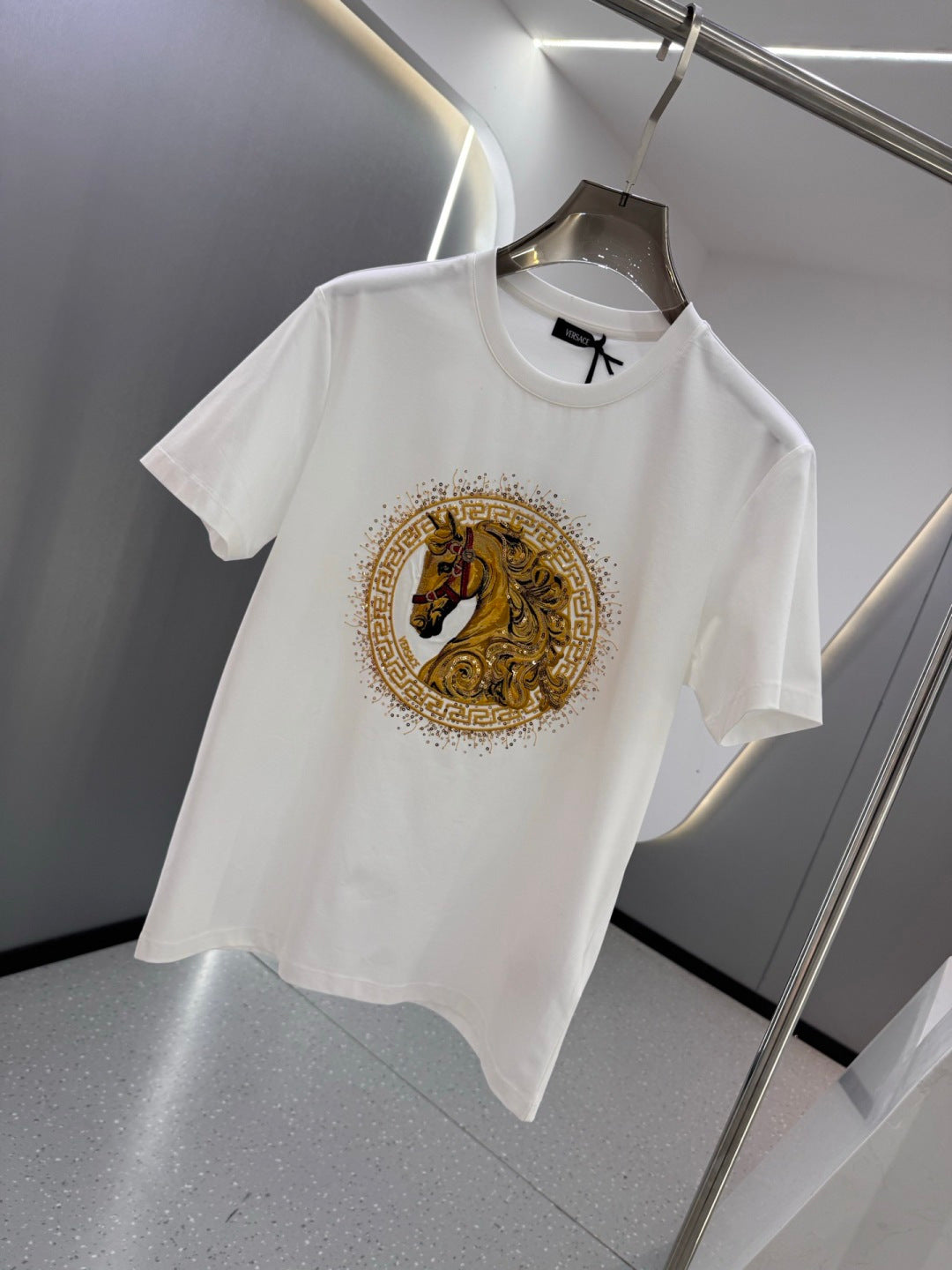 White crew-neck T-shirt featuring a gold horse crest emblem on the chest
