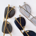 Dior sunglasses with gold and clear frames, dark lenses laid out
