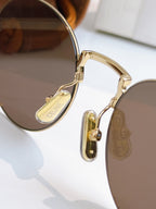 Gold round sunglasses side view with metal hinge and tinted lenses