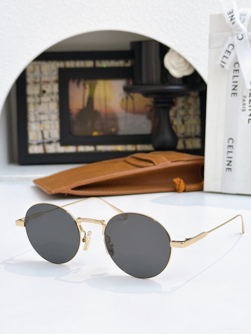 Round gold-frame sunglasses with dark gray lenses and thin metal arms.