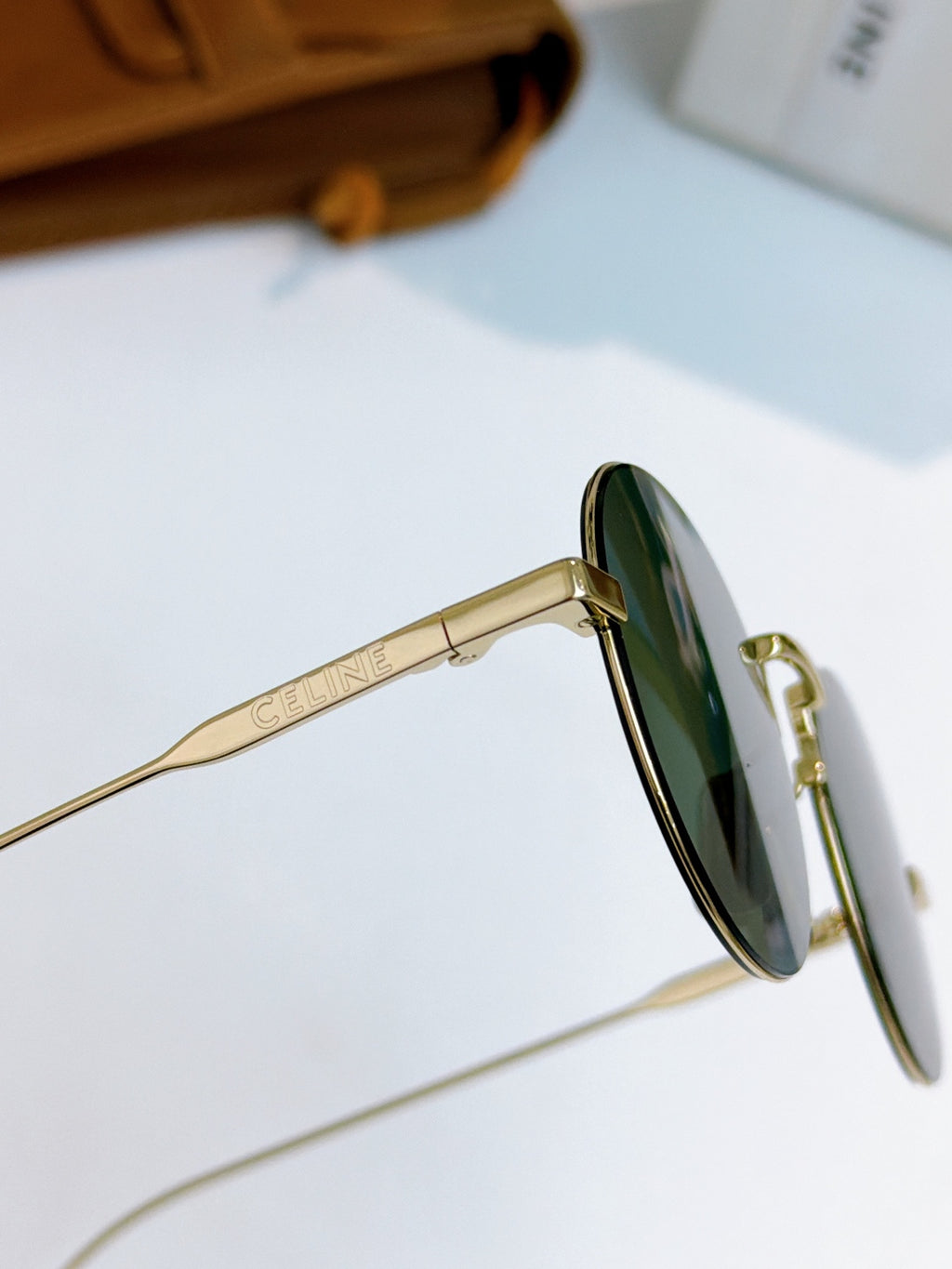 Gold round sunglasses side view with green-tinted lens and metal frame