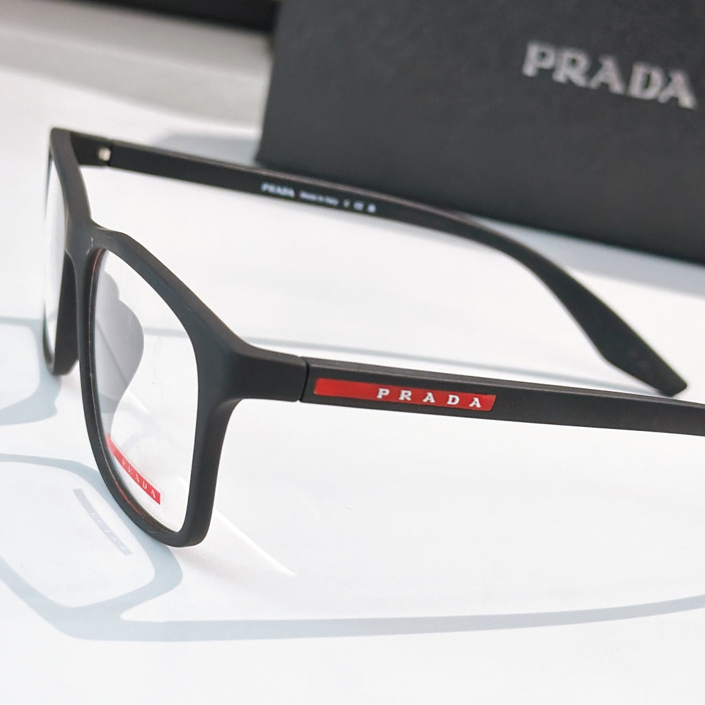 Prada glasses close-up, black frames and PRADA logo bar on temple