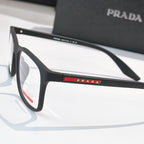 Prada glasses close-up, black frames and PRADA logo bar on temple