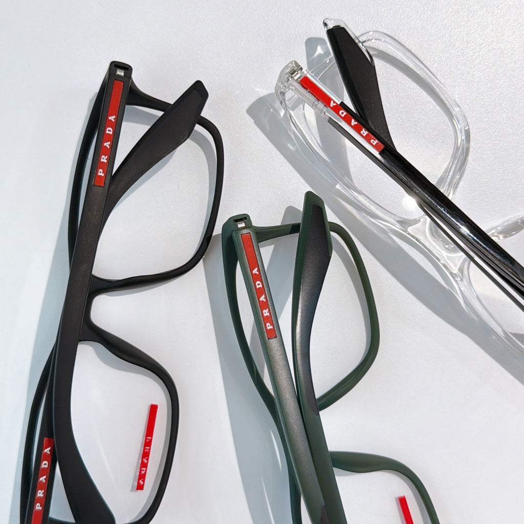 Prada glasses set: black, green, and clear frames with red PRADA logos