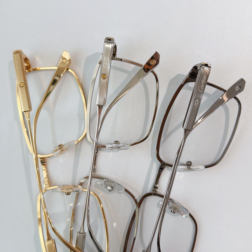 Cartier glasses set with gold, silver, and gray frames on clear lens fronts
