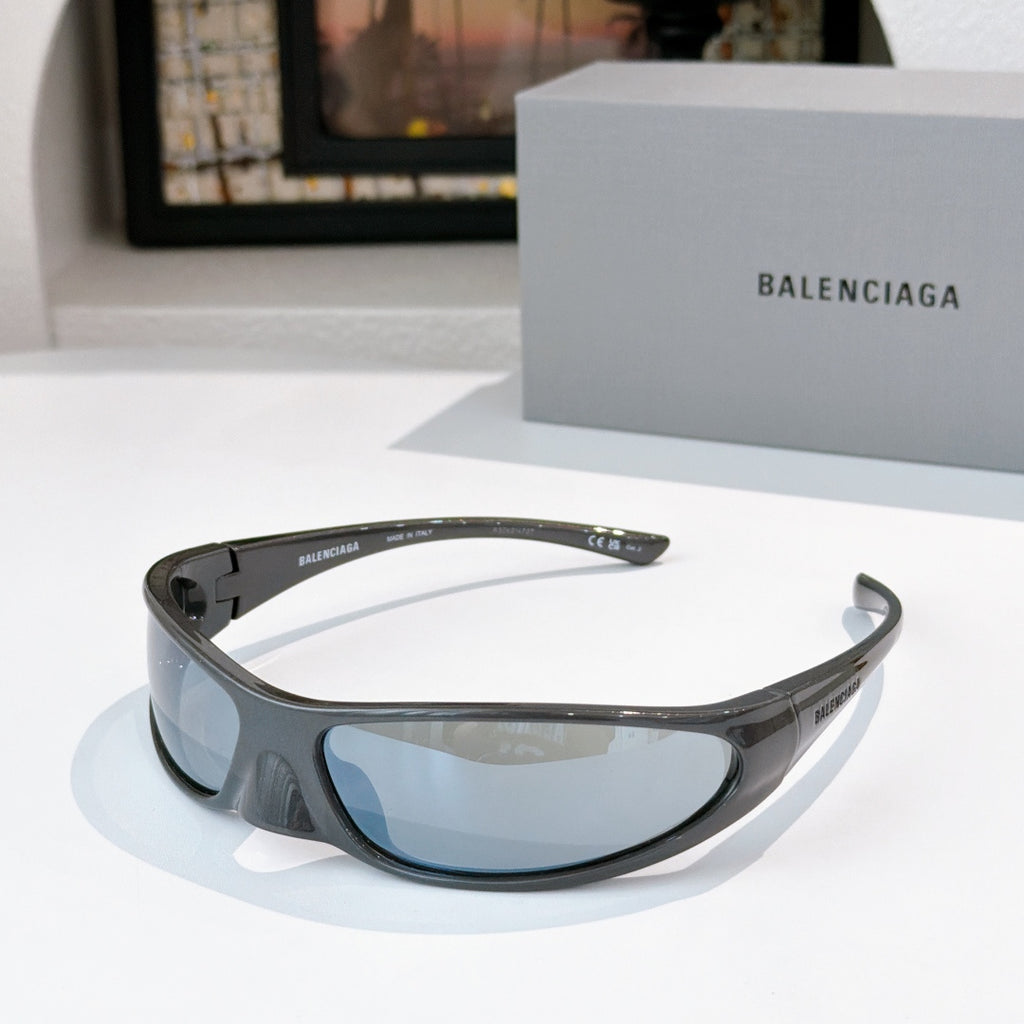 Balenciaga sunglasses with dark gray frames and light blue lenses, curved wrap style.