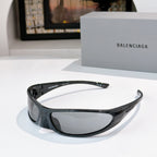 Balenciaga sunglasses with black frames and smoke lenses, curved wrap silhouette.