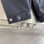 Dark jacket cuff with snap button and round rubberized detail