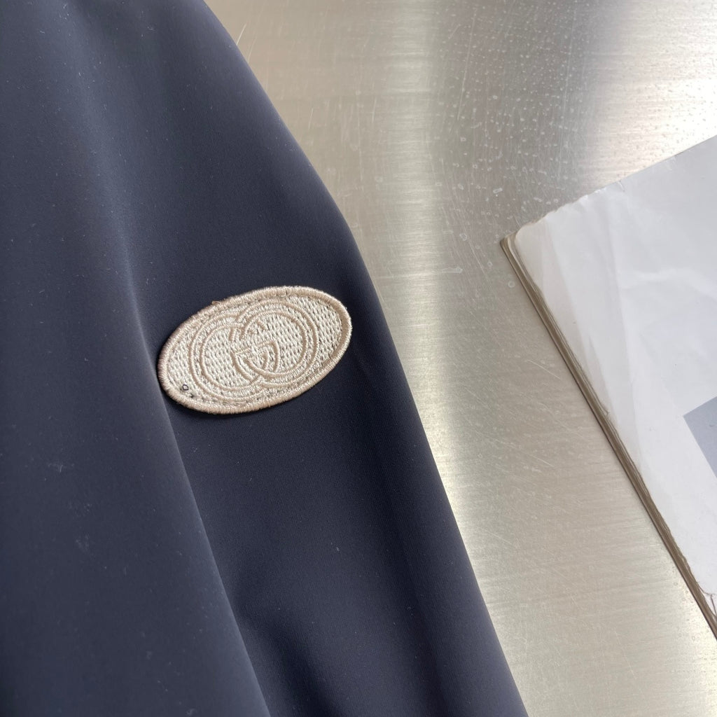Dark jacket sleeve with embroidered GG-style crest patch
