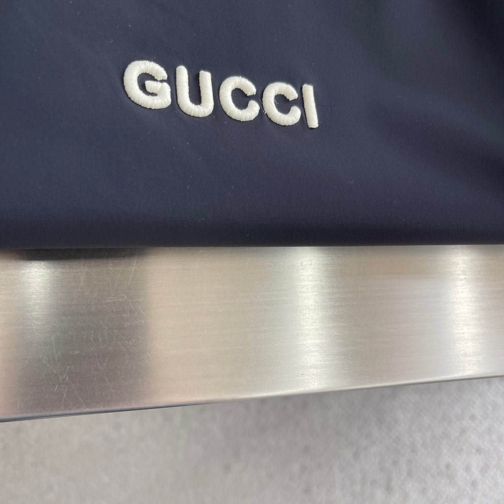 Dark Gucci jacket panel with raised white Gucci logo lettering