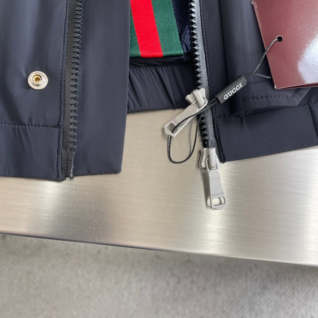 Dark jacket front zipper, stripe lining visible, hanging interior tag