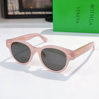 Sunglasses with pink frame, dark lenses, and gold-patterned temples