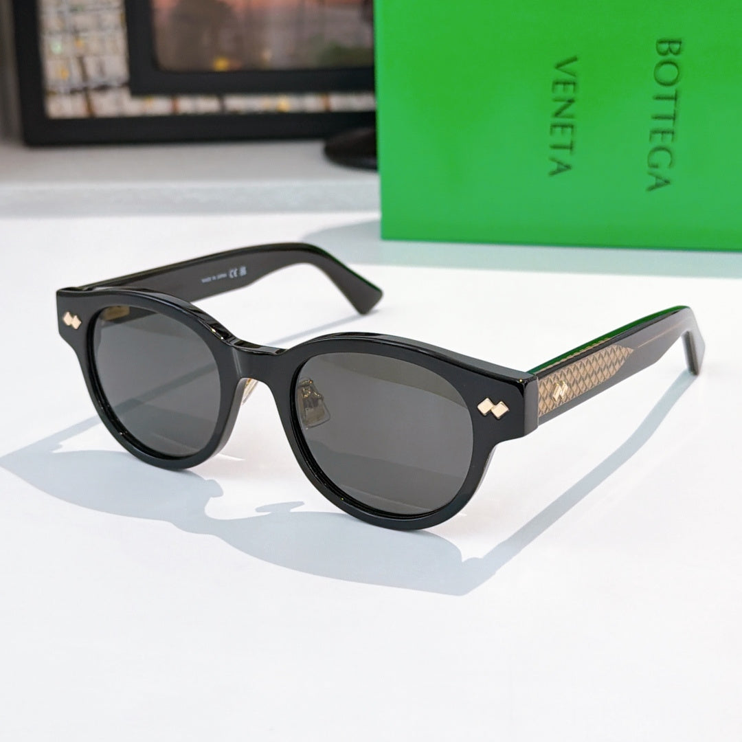 Sunglasses with black frame, gray lenses, and gold-patterned temples