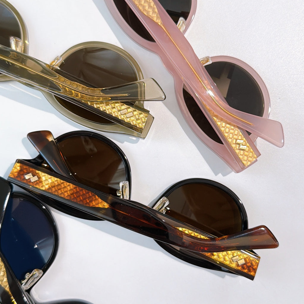 Sunglasses close-up with pink and black frames, gold-patterned temples