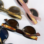 Sunglasses close-up with pink and black frames, gold-patterned temples