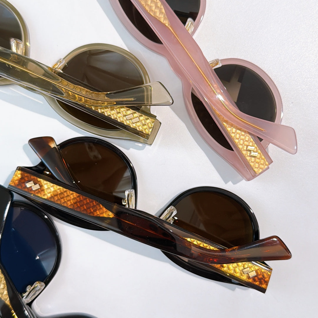 Sunglasses close-up with pink and black frames, gold-patterned temples