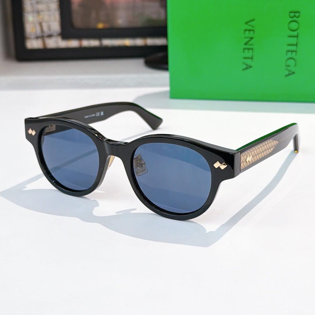 Sunglasses with black frame, blue lenses, and gold-patterned temples