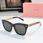 MiuMiu sunglasses with black frames, dark lenses, and gold logo on temple arms