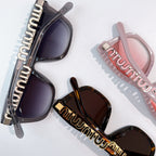 MiuMiu sunglasses with dark lenses and tortoiseshell temple arms, logo detail visible