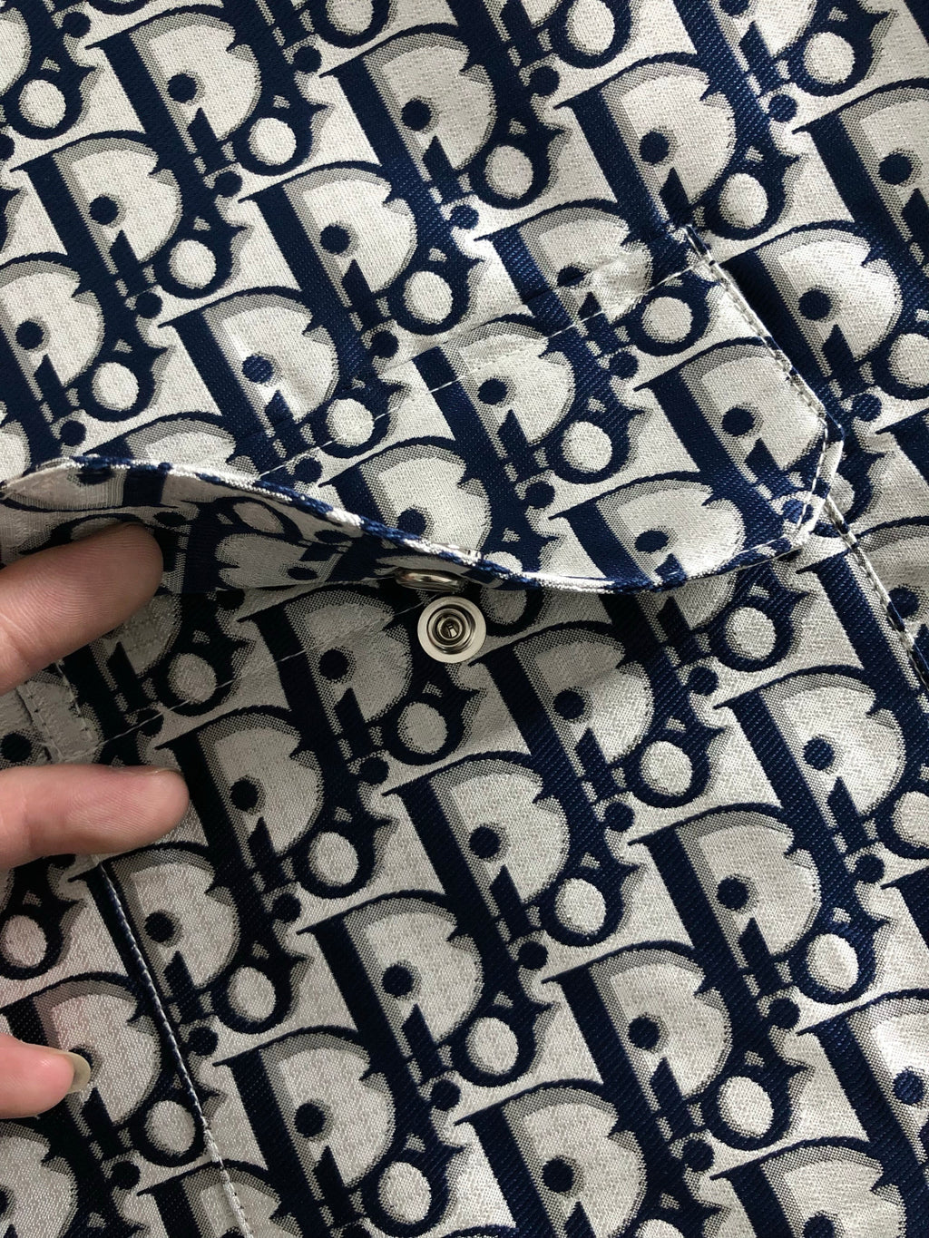 Close-up of Dior monogram jacket zipper seam with metal pull tab.