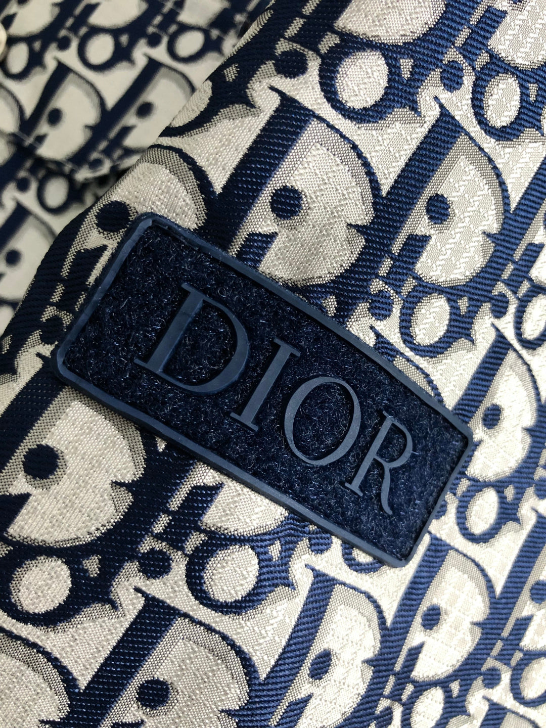 Close-up of Dior monogram fabric with black DIOR label tab and trim.