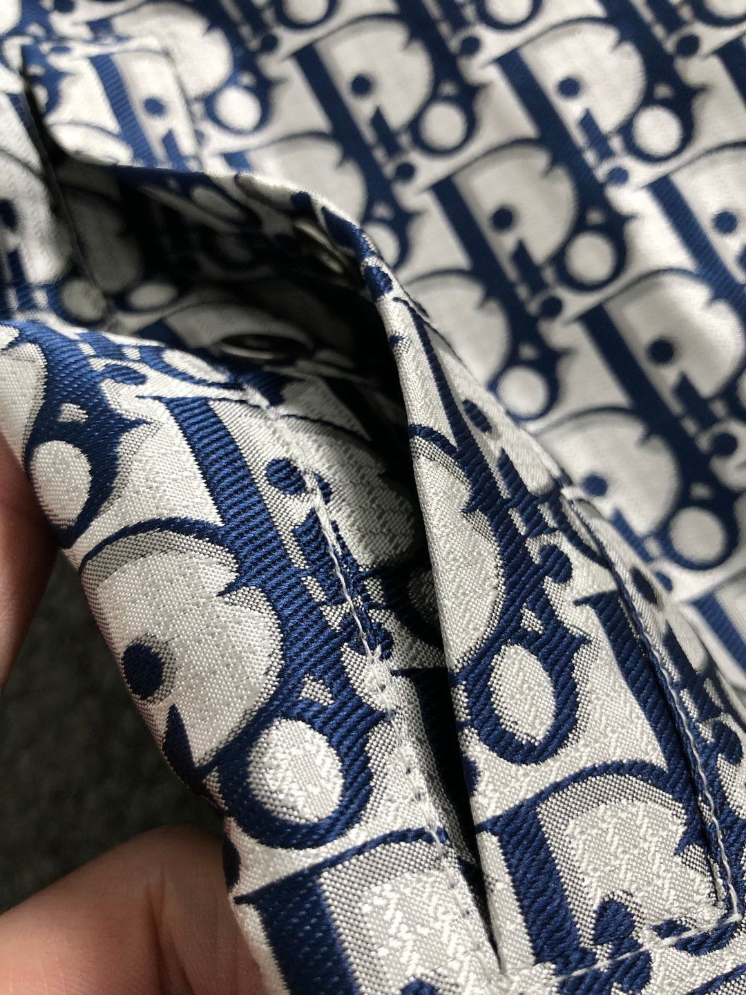 Close-up of navy-and-white Dior monogram fabric, sleeve cuff detail.