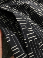 Black jacket fabric with large zigzag geometric logo pattern