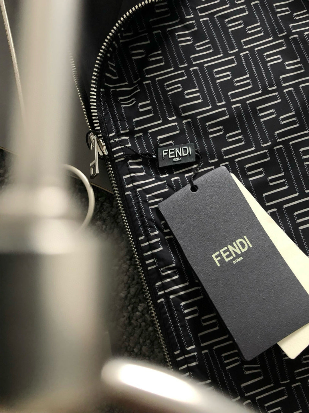 Close-up of black logo-pattern jacket zipper with Fendi logo patch