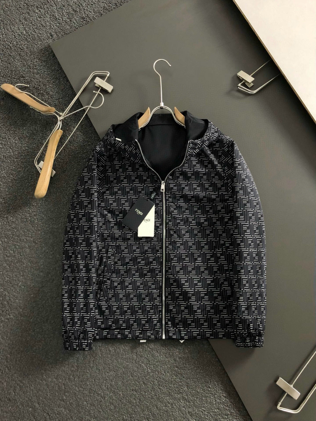 Black zip jacket with repeating geometric logo print and front zipper