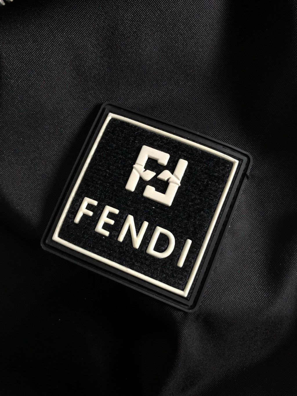 Metal Fendi logo emblem on black fabric patch