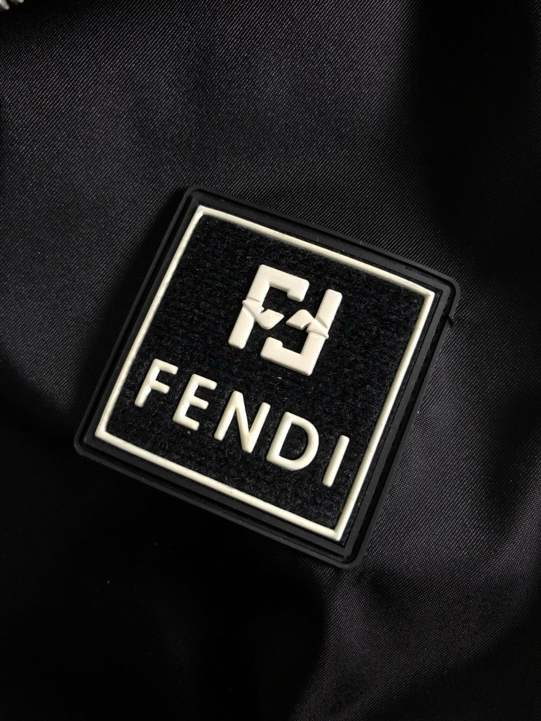 Metal Fendi logo emblem on black fabric patch