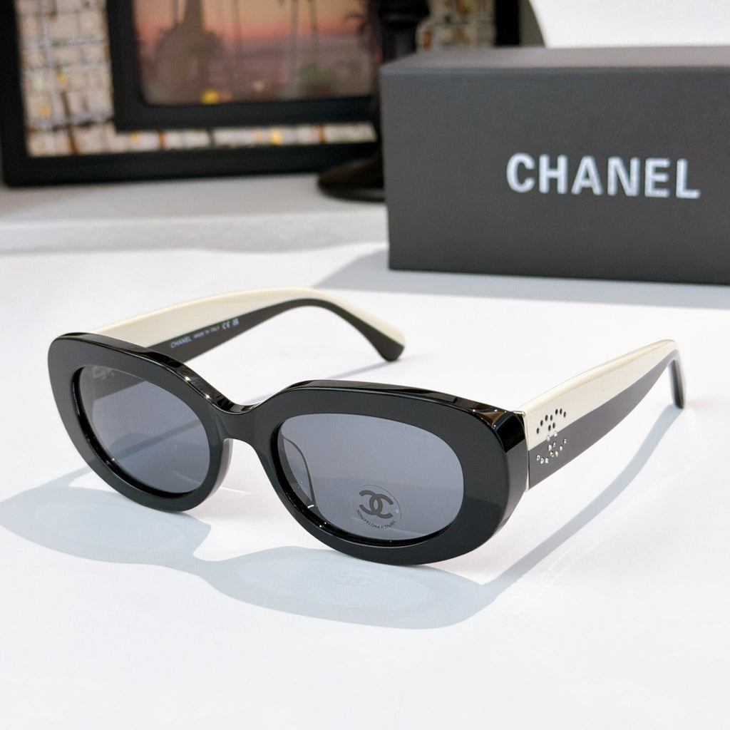 Chanel sunglasses with black frames, cream temples, gray lenses and logo emblem detail