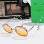 Oval sunglasses with amber tinted lenses and thin gold-tone metal frames.