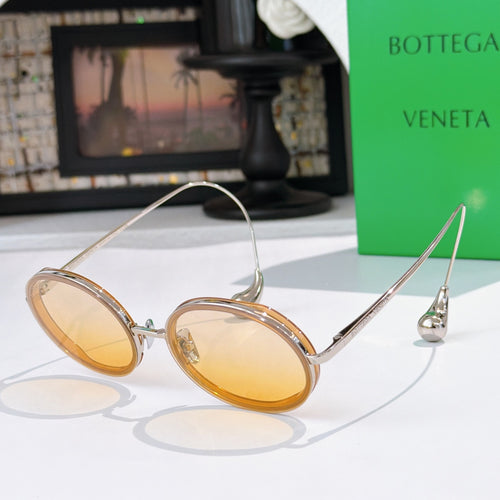Oval sunglasses with amber tinted lenses and thin gold-tone metal frames.