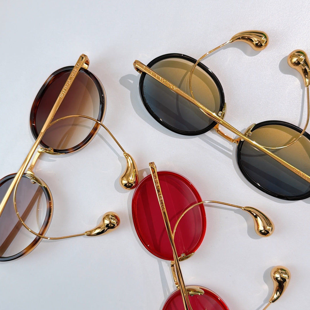 Assorted oval sunglasses with gold-tone frames and mixed colored tinted lenses.