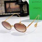 Oval sunglasses with warm brown tinted lenses and gold-tone metal frames.