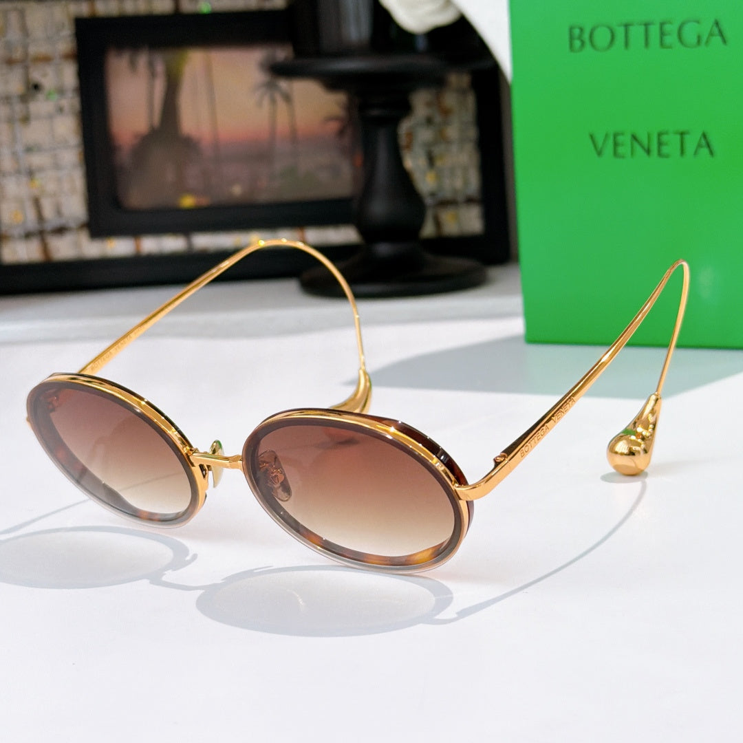Oval sunglasses with warm brown tinted lenses and gold-tone metal frames.