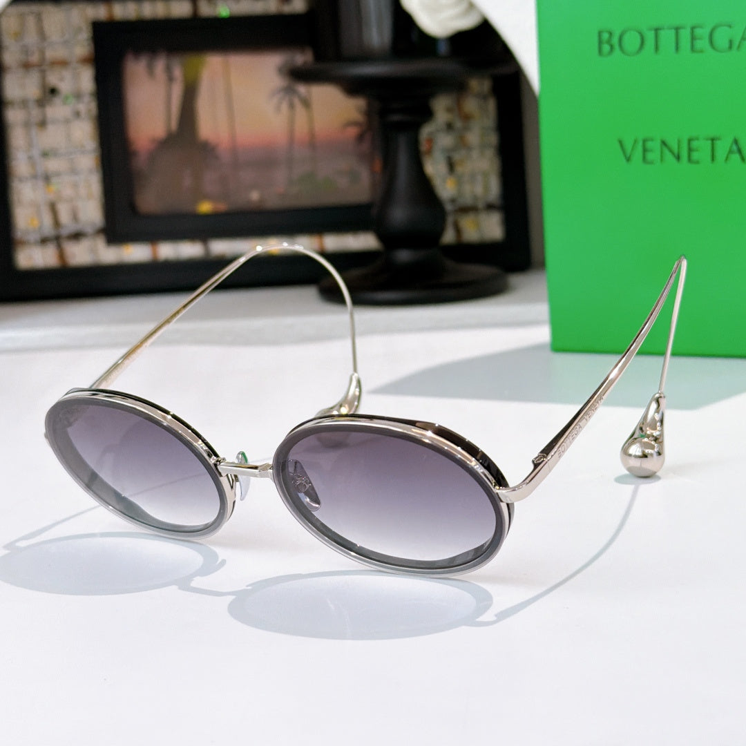 Oval sunglasses with purple tinted lenses and dark frame with silver-tone metal details.