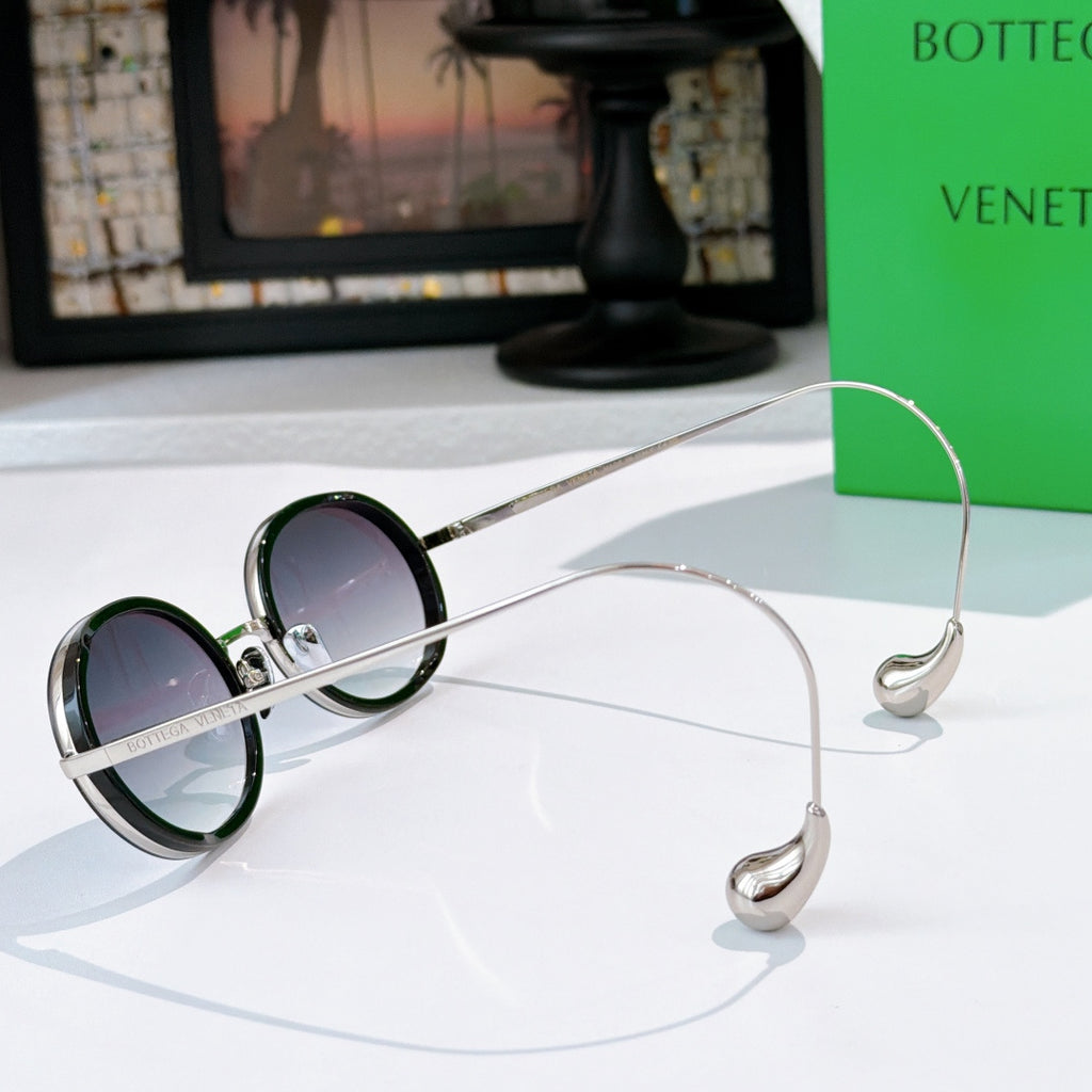 Oval sunglasses with dark lenses and silver-tone metal frames; side profile view.