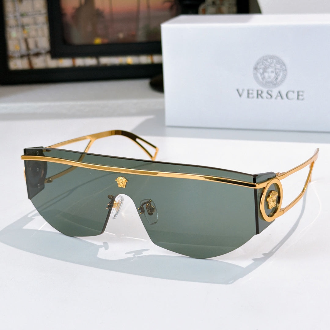 Gold-tone sunglasses with greenish lenses and round emblem at the side