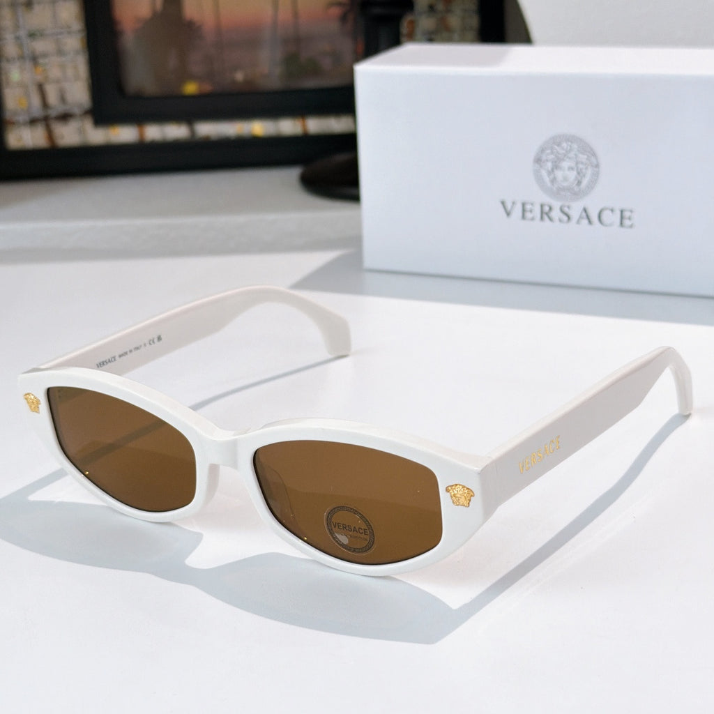 White cat-eye sunglasses with brown lenses and gold emblem temple details