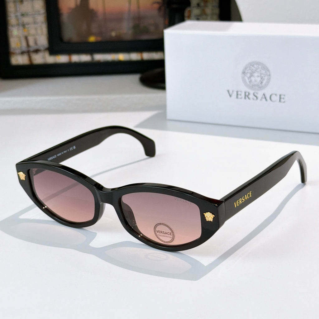 Black cat-eye sunglasses with purple-tinted lenses and gold emblem temple details