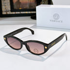 Black cat-eye sunglasses with purple-tinted lenses and gold emblem temple details
