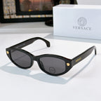 Black cat-eye sunglasses with gray lenses and gold emblem temple details
